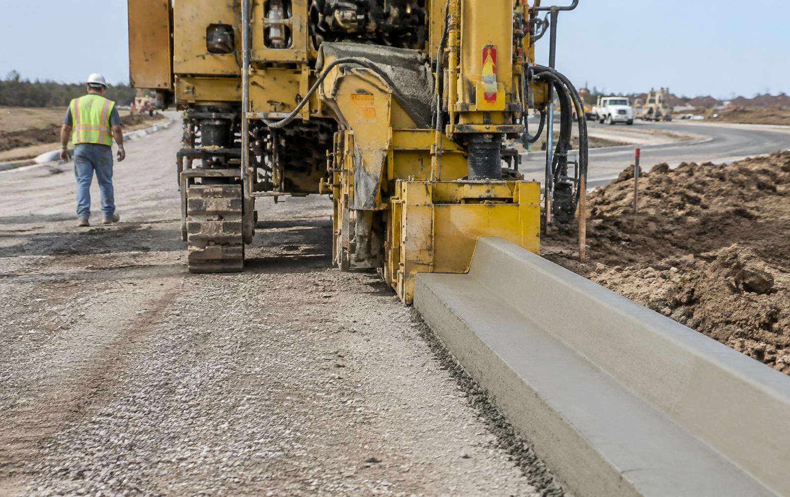 Concrete curb and gutter being machine-extruded along a new roadway